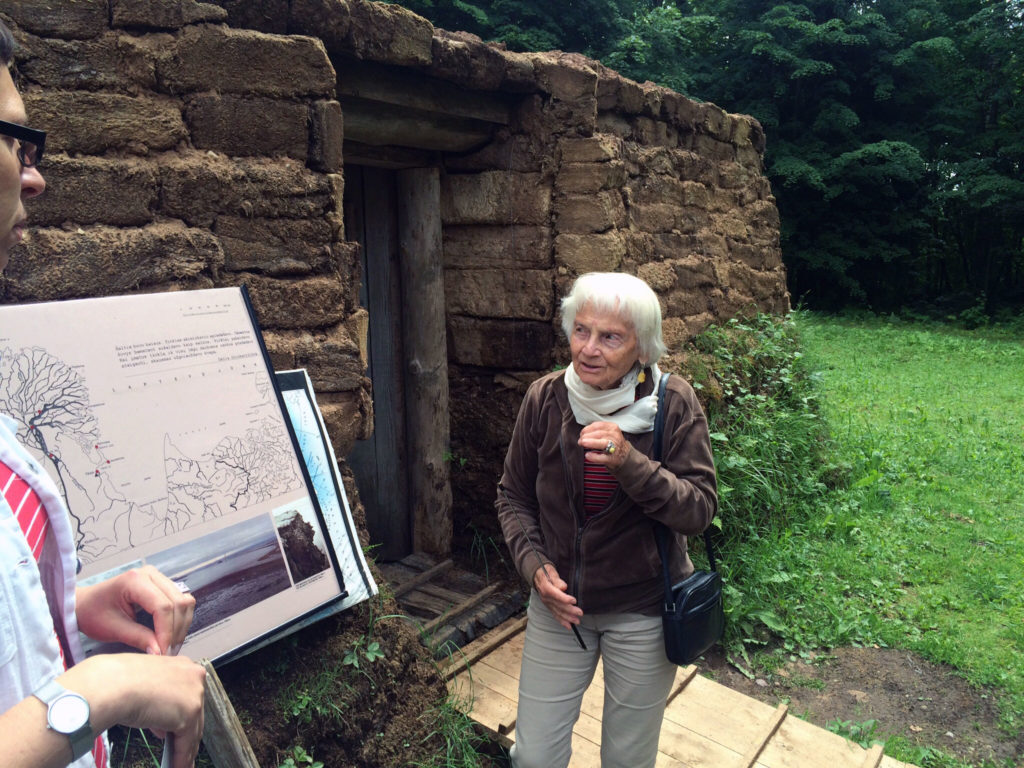 a lady in front of a sod house