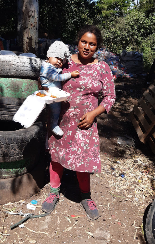 a woman in dirty clothes holding a baby
