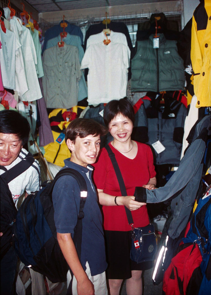 Lee and a sales lady in a crowded clothes market
