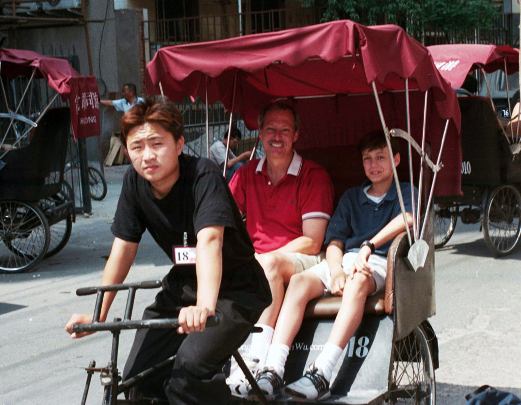 a Chinese man peddling a pedicab with Chip and Lee