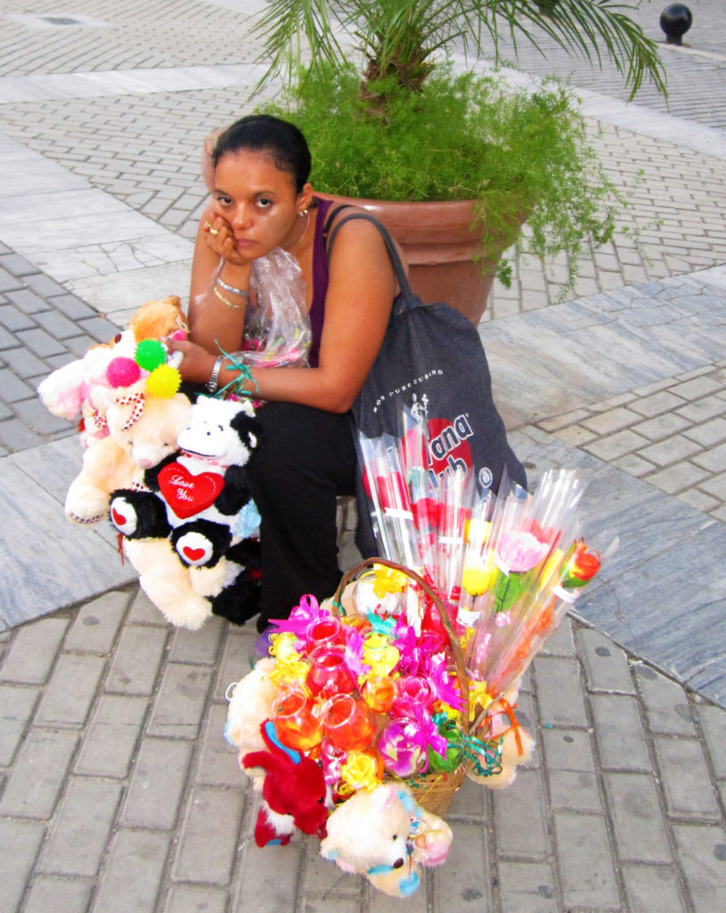 a bored lady sitting on the street with her merchandise