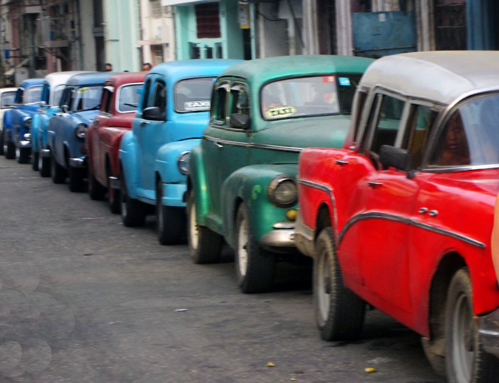 a line of old cars parked on a Havana street