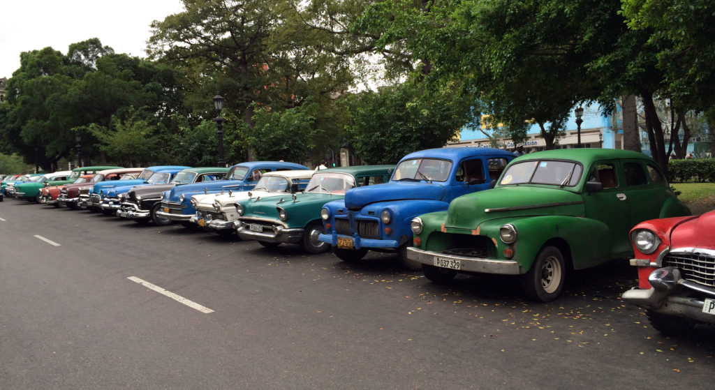 A long line of cars from the 1950s parked, waiting customers near the Fine Arts Museum in Havana