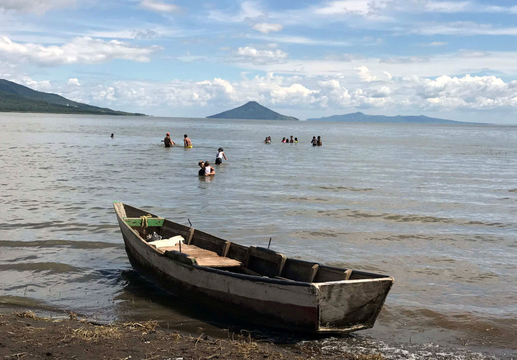 a boat on a brown lake with swimmers in the background