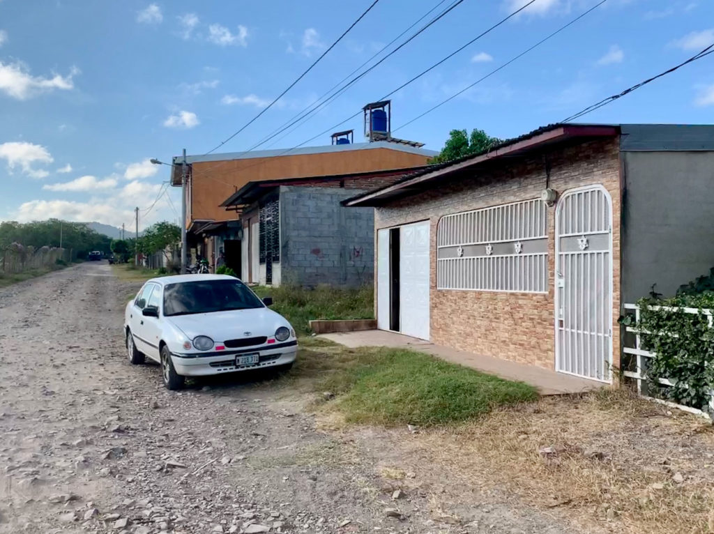 an older Toyota Corolla in front of a simple Nicaraguan home