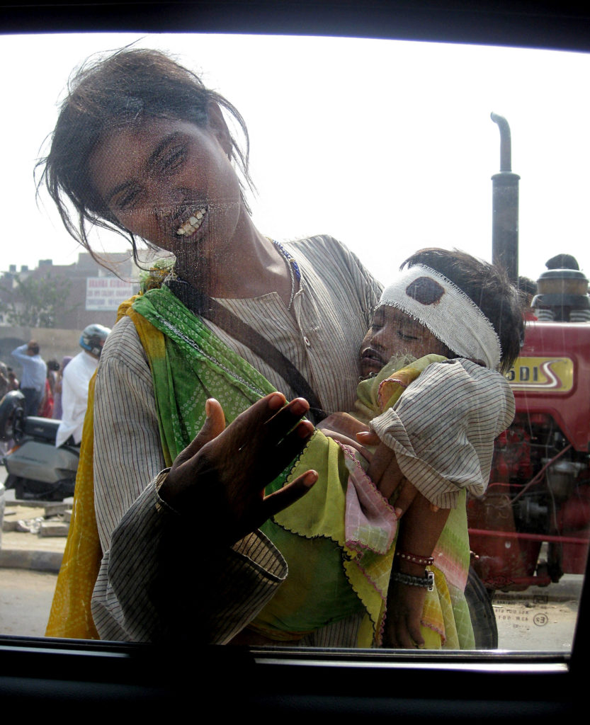 a dirty woman begging while holding a baby