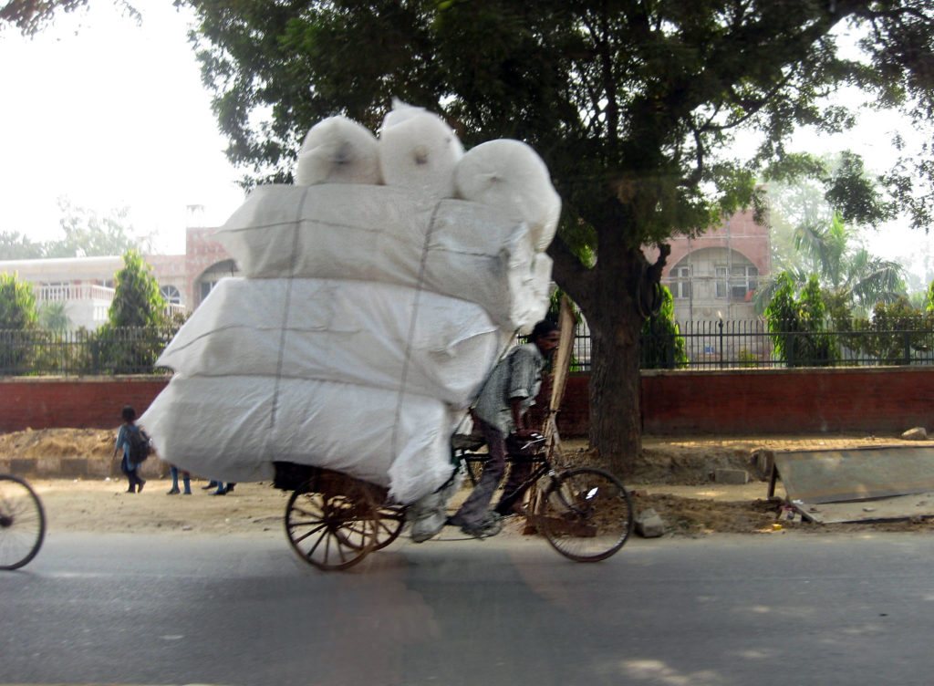 a guy on a bike with a load towering over him