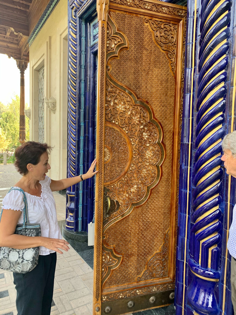 a well-dressed woman admiring tall carved doors