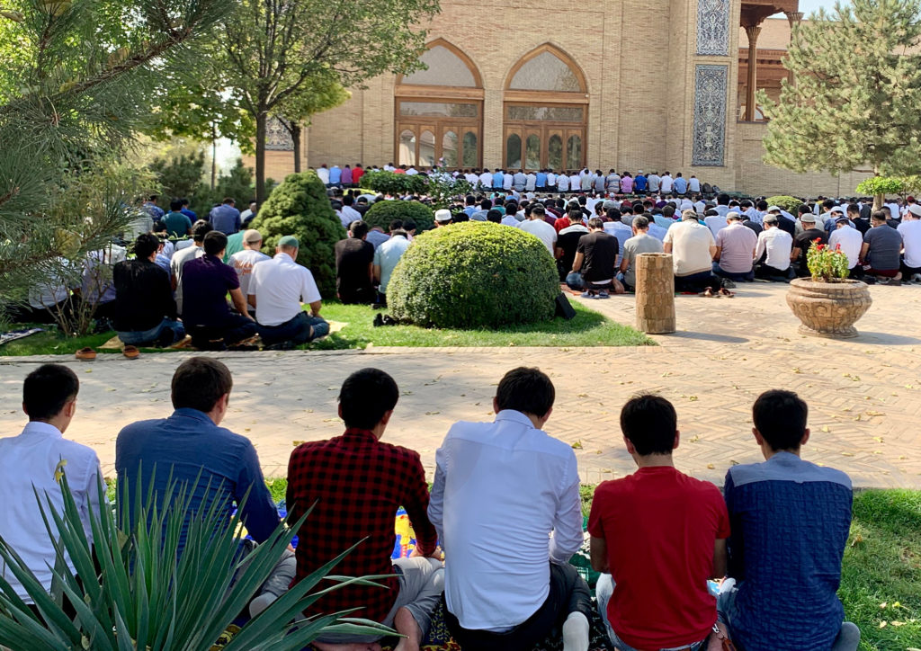 men sitting on the grass outside a mosque