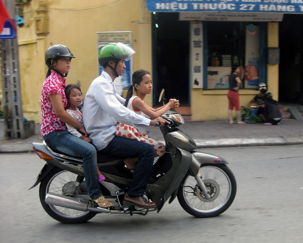 two parents and two girls on a small motorcycle