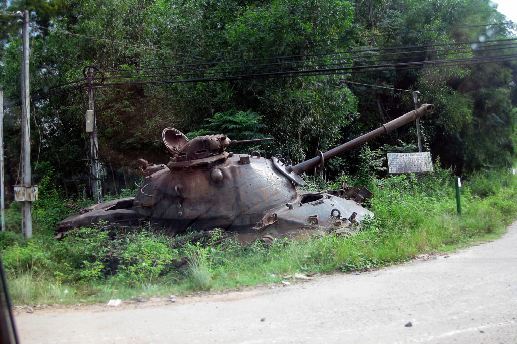 an old American tank surrounded by weeds